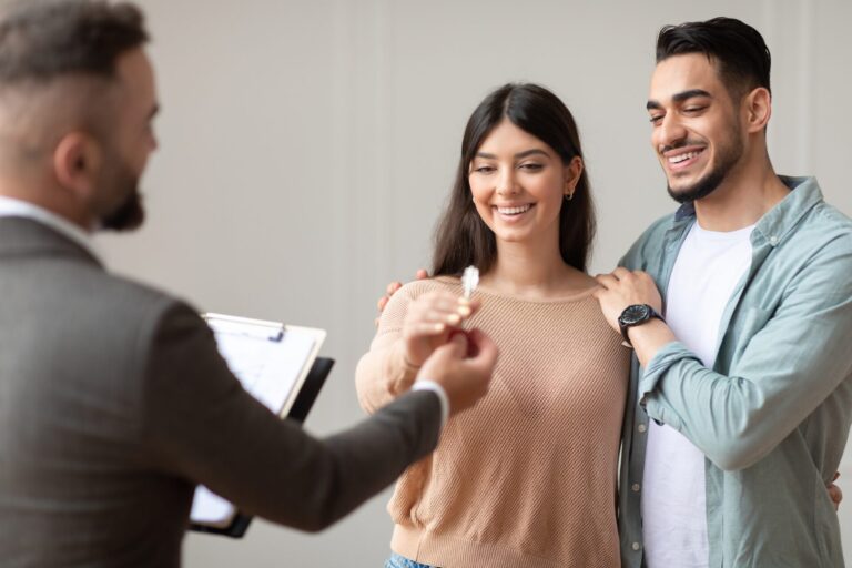 Young couple receiving house keys from an estate agent in Stafford buy-to-let property transaction