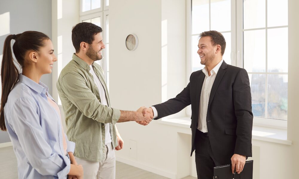 Estate agent shaking hands with a couple inside a bright property after a successful home viewing, representing the buying and property opportunities available when living in IP2 Ipswich, including Chantry and Stoke.