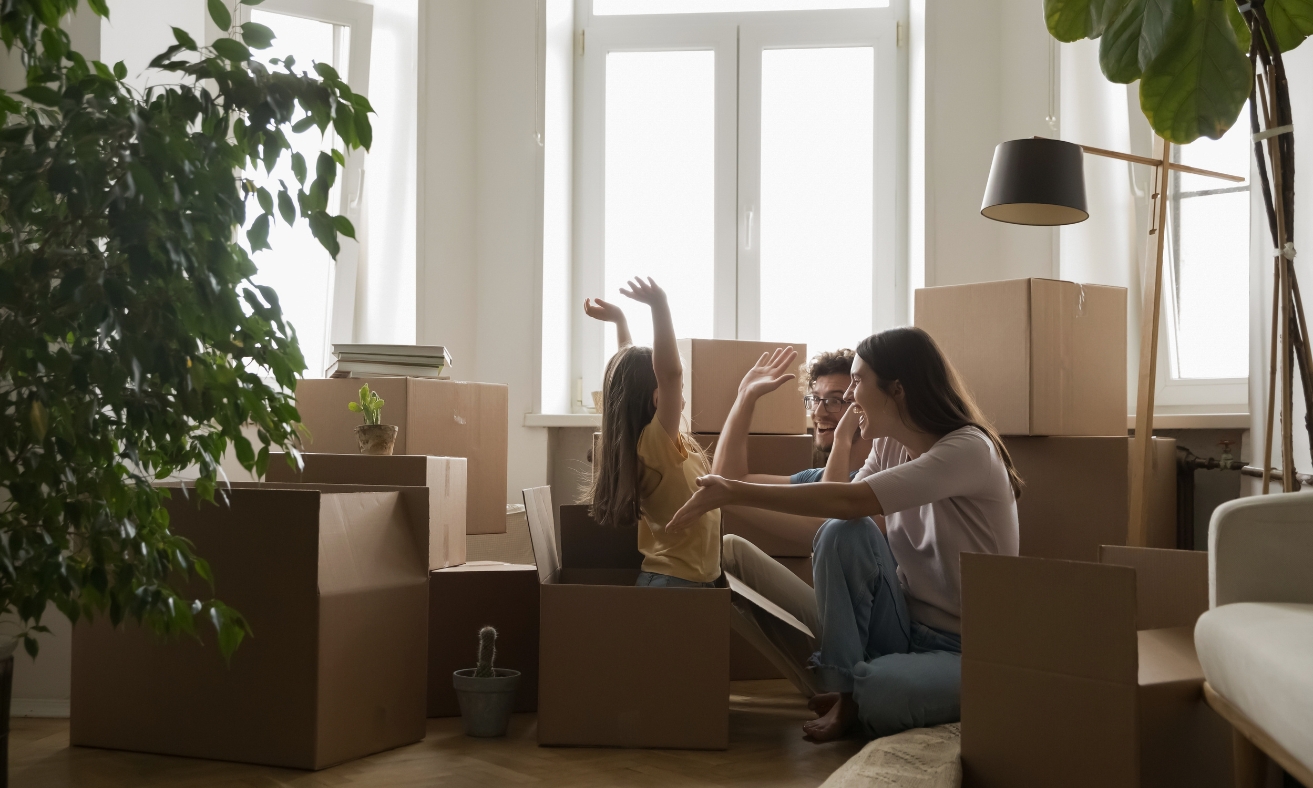 A young family sits among moving boxes in their new home, celebrating moving day. The image reflects the journey of first-time buyers purchasing a property in Shrewsbury's SY1 and SY2 neighbourhoods.