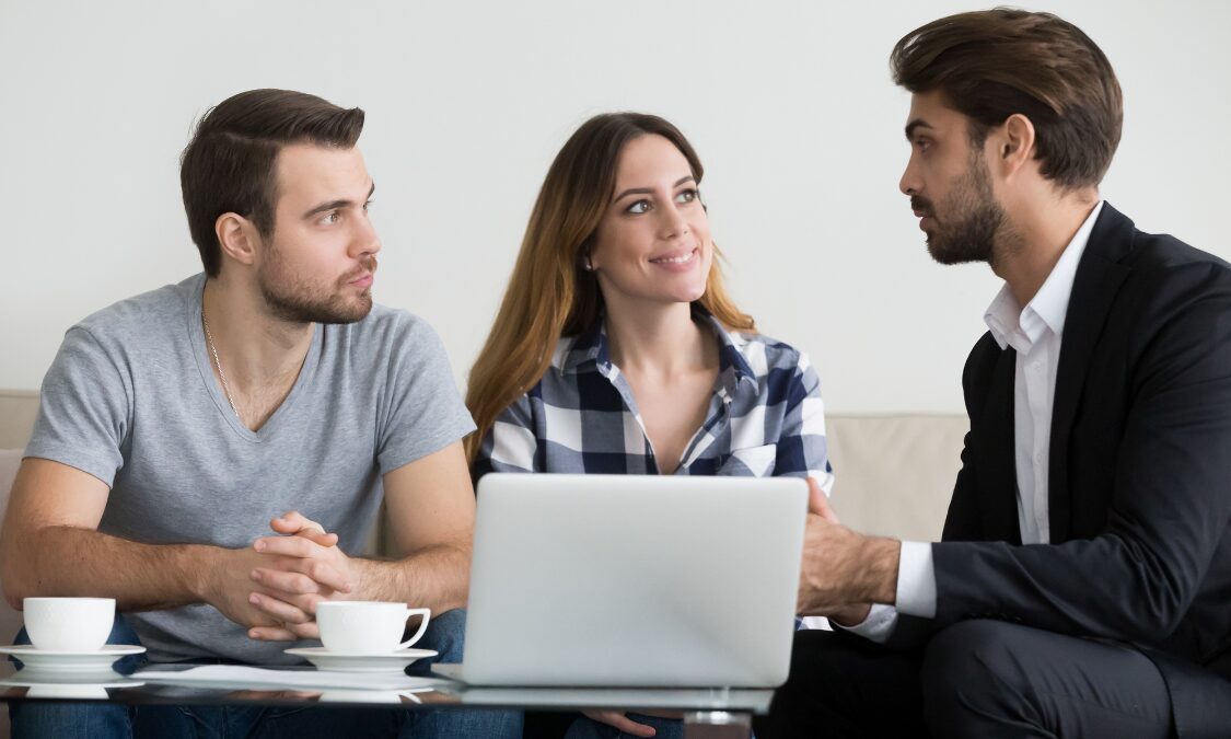 A couple meeting with a property estate agent to discuss buying a home, representing buyers exploring property for sale in Stafford ST18 villages and the local housing market.