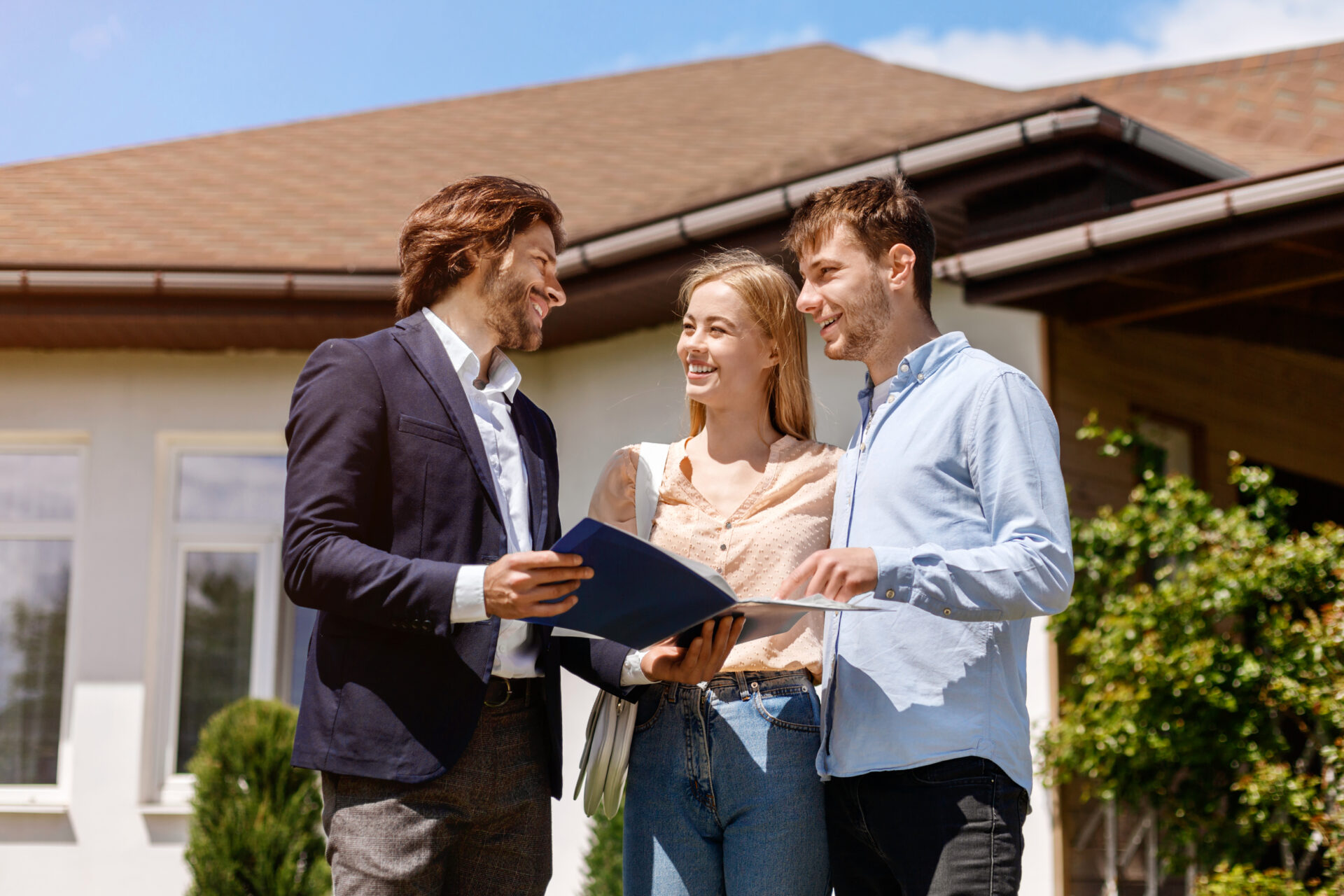 Letting agent discussing property documents with a couple outside a home, representing landlord compliance and rental advice in Tadley.