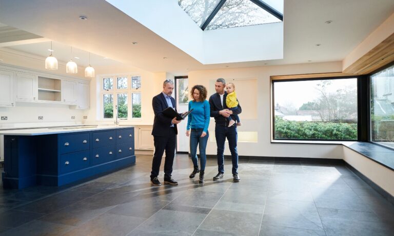 Estate agent showing a modern, energy-efficient home to prospective landlords or buyers during a property viewing, illustrating the type of well-insulated home discussed in the article about EPC upgrades for Christchurch rental properties.
